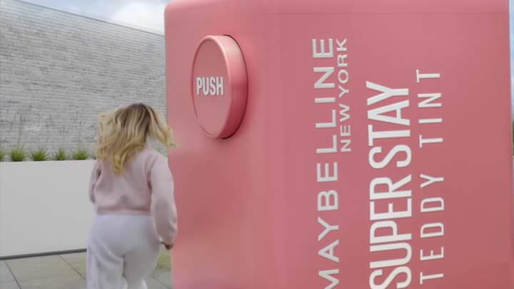 A giant Teddy Tint product box standing on a rooftop against the sky.