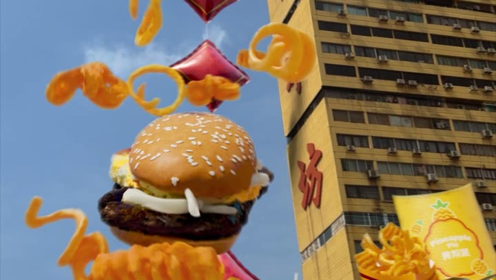 The burger hanging over a Singapore shophouse street with curly fries and red lanterns around it.