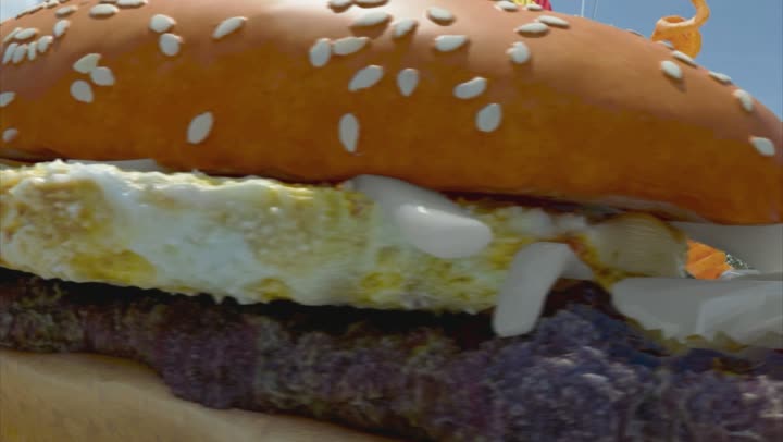 A macro of the burger: sesame bun, egg and patty in close detail.